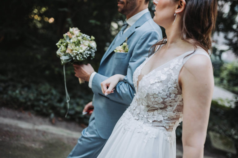 Hochzeitspaar geht eingeharkt und mit Brautstrauß nebeneinander