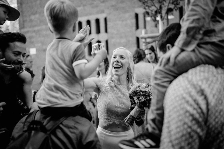 Die Braut gibt einem Jungen, der auf Schultern sitzt, ein High-Five