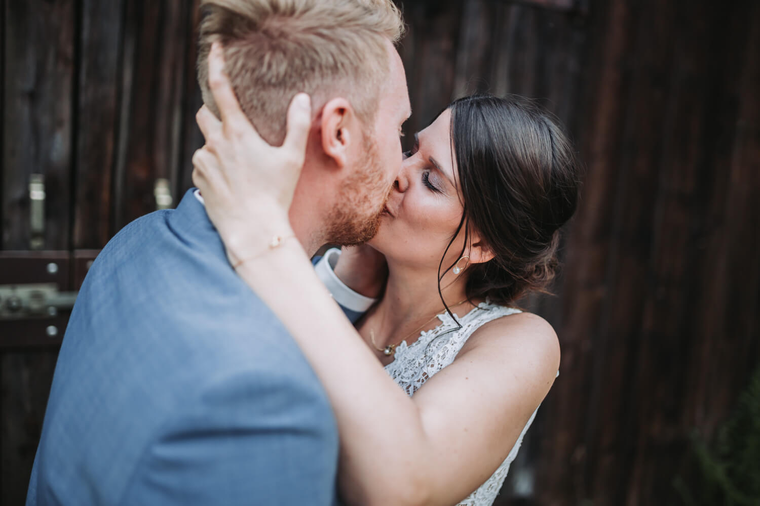 Ein Hochzeitspaar küsst sich innig vor einem Scheunentor