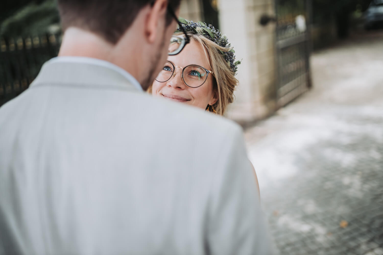 Der Bräutigam steht mit dem Rücken zur Kamera und man sieht nur die Braut, die ihrem Ehemann tief in die Augen schaut.